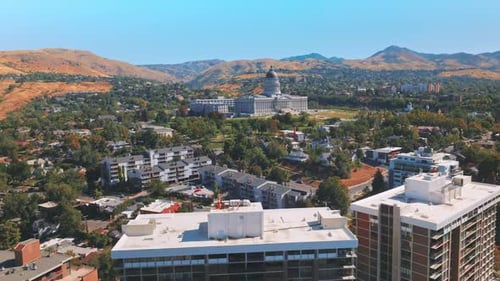 Beautiful Utah State Capitol surrounded by greenery and modern houses. Brown bare mountains