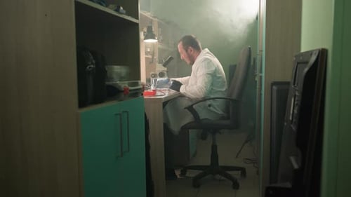 Scientist Working Under Microscope in Smoky Lab