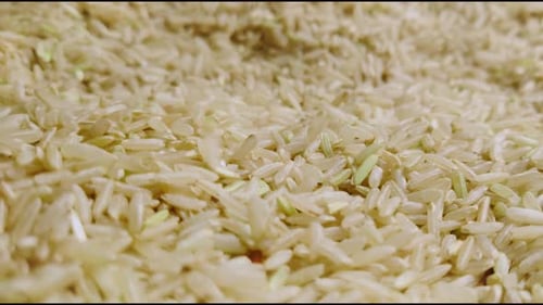 Reis, der auf einen Haufen braunen Reis fällt - Makroaufnahme, 4k