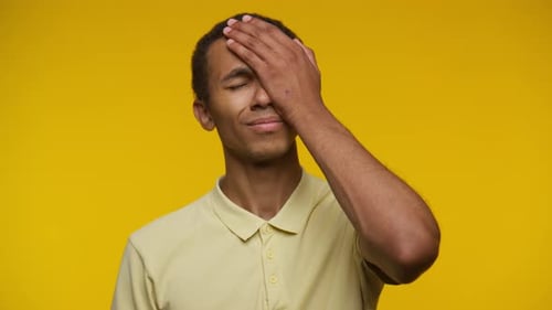 Young Adult Face Palm in Front of Yellow Background
