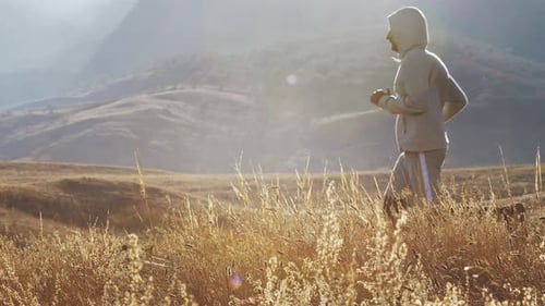 A Person Does a Cardio Run Among the Mountains at Sunset
