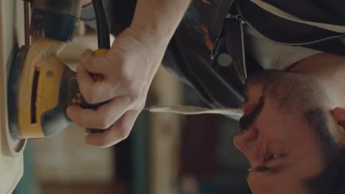 Man Sands Wood with Orbital Sander in Shop
