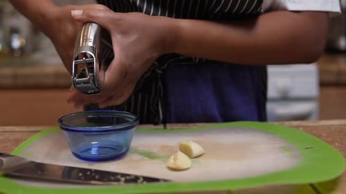 Using a garlic press to mince a whole clove of fresh garlic - slow motion
