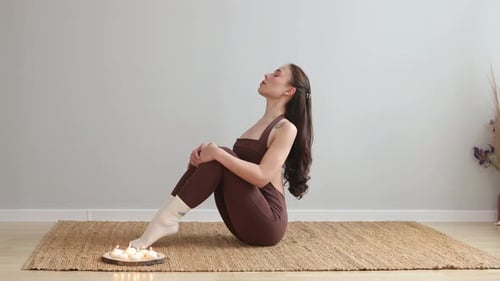 Young Woman Practicing Yoga Balance Pose with Raised Leg Near Candles at Home Female Sitting on Mat