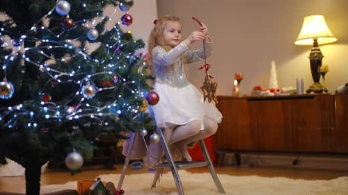Little Girl Decorates Christmas Tree with Ornament