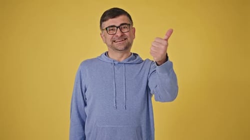 Mood Swing Cheerful MiddleAged Man Showing Like and Dislike Gestures on Yellow Background