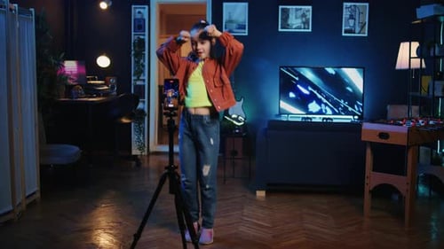 Girl dances for phone mounted on tripod indoors