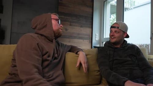 Two Young Men Conversing Indoors on a Couch