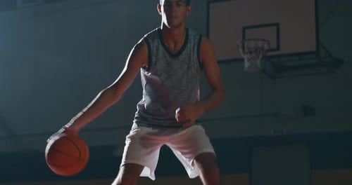 Cinematic slow motion shot of an young professional male player is practicing a basketball work ou