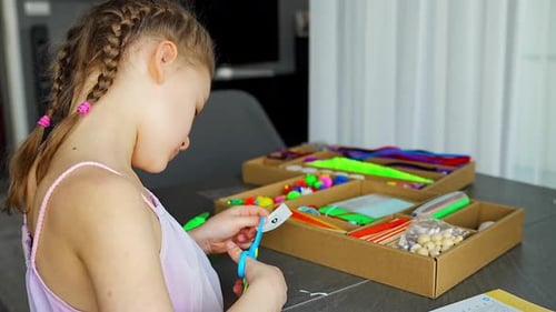 Little Girl Cutting Paper with Scissors While Making Craft at Table with Colorful Materials Kids