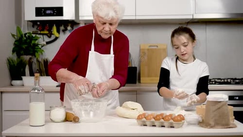 Schönes Mädchen spielt mit Mehl Viel Spaß, während Oma selbstgemachte Kuchen kocht Großmutter