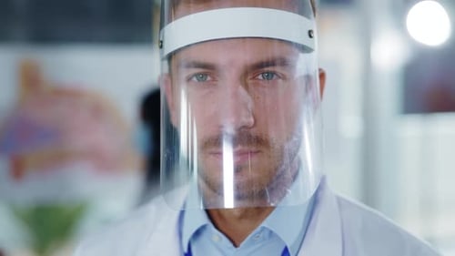 Doctor in Face Shield Looks Directly at Camera