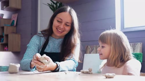 Smiling Woman and Girl Sculpting Clay Together Indoors