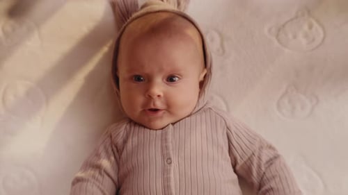 Cute Funny Little Newborn Baby Smiling Lying at the Back in the Child Crib Looking Around Portrait