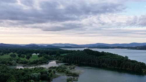 Drone Flying Over Green Forest and Lake Under Cloudy Sky