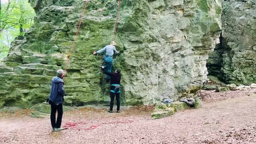 A woman learns rock climbing with the help of an instructor.