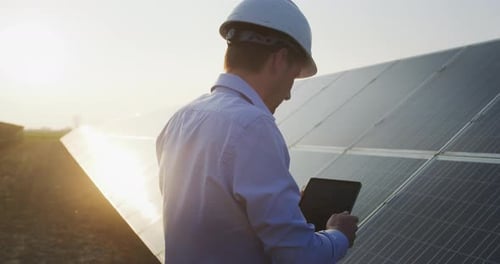 Ein junger Ingenieur überprüft mit einem Tablet den Betrieb von Sonne und Sauberkeit auf dem Feld der Photovoltaik