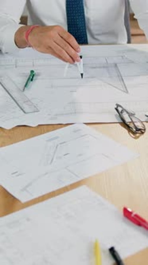 Architect Draws Blueprints at Desk in Workplace
