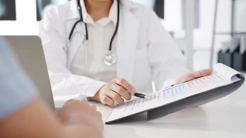 Female Doctor Reviews Patient Chart in Clinic