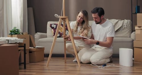 Delighted Young Adorable Wife with Handsome Husband Reading Instruction of Floor Lamp Decorating