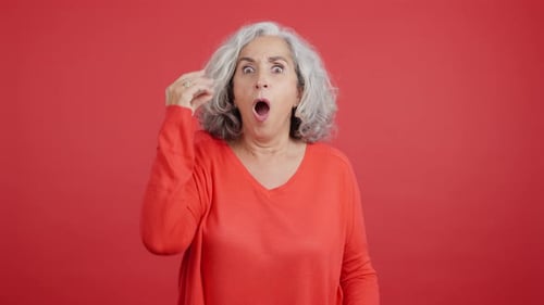 Surprised Woman with Gray Hair Reacts on Red