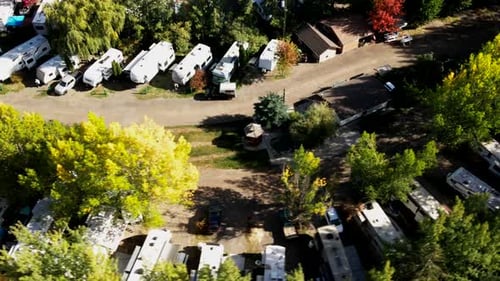 Luftaufnahme eines Wohnmobilparks im Herbst mit vielen Campern entlang der Straße, geparkt auf einem Campingplatz