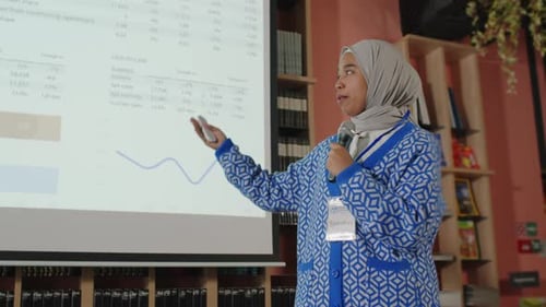 Muslim Girl in Hijab Giving Presentation during Conference in College Library