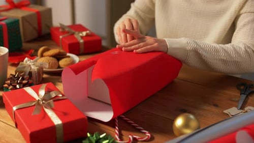 Woman wrapping a Christmas gift with red paper