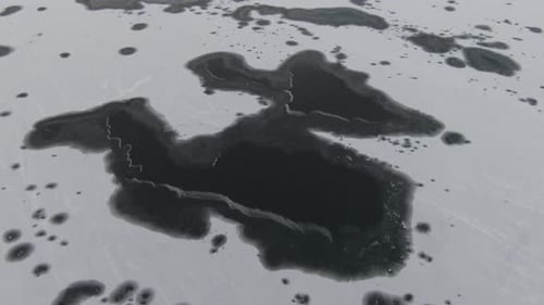 Frozen lake from above with black and white patterns from ice. Dolly back