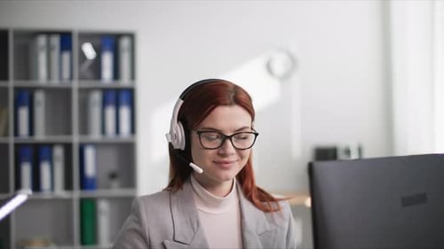 Tech Support a Young Woman Works in a Call Center and Advises a Client Talking on a Microphone on