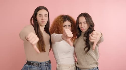 Three Serious Women Giving Thumbs Down