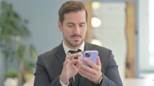 Man Using Smartphone in Business Suit at Workplace