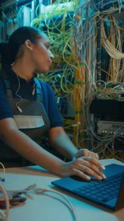 Woman Working on Laptop Near Servers