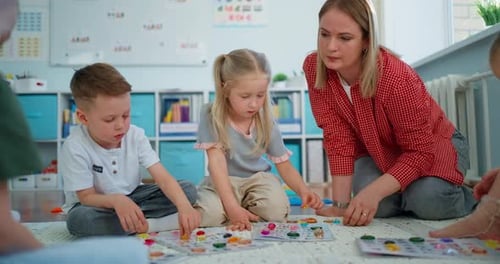Young Children Sitting on a Classroom Floor Playing with Colorful Educational Pieces Focusing