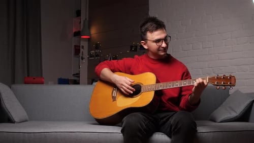 Young Man Playing Acoustic Guitar on Couch