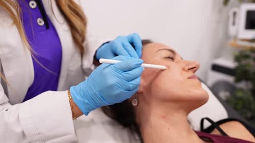 Cosmetologist Preparing Patient's Skin for Facial Biostimulator Treatment