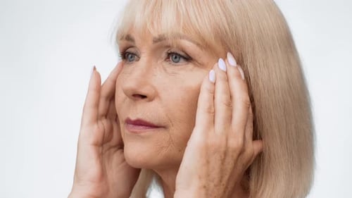 Senior Woman Touches Face in Close Up