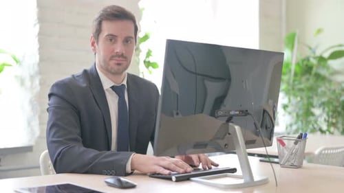 Man Types at Computer, Looks Up and Smiles