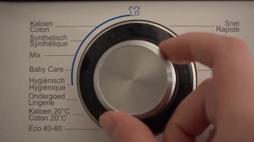 Close up Dutch language washer dial set to Wool by Caucasian hand