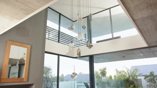 Modern living room with large windows overlooking pool and outdoor seating area, at home