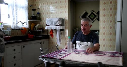 Senior man seated at kitchen table alone