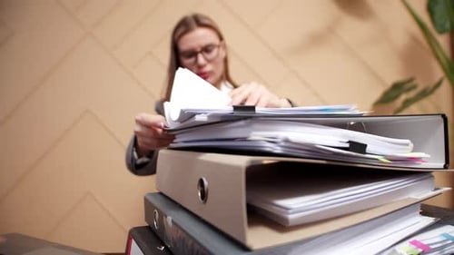 Closeup of Folders with Working Office Documents Against Background of Woman Office Worker Sorting
