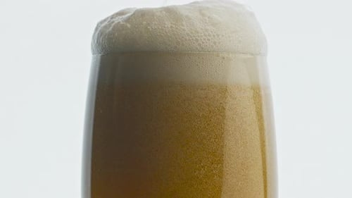 Refreshing craft lager stream creates foaming bubbles in transparent glassware