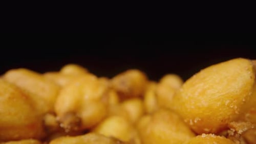 Dried corn kernels with spices on a black background. Dolly slider extreme close-up.