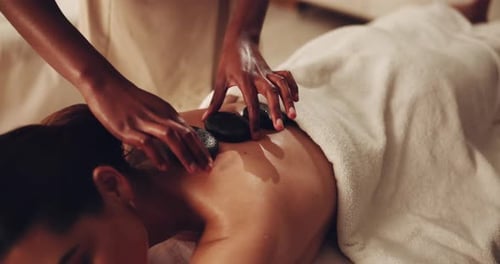 Woman, hands and hot rocks with masseuse for physical therapy, deep tissue massage or zen at spa
