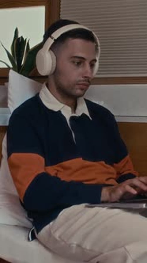 Man in Headphones Using Wireless Laptop at Home Office
