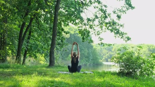 Young Adult Woman Doing Yoga by Calm Lake