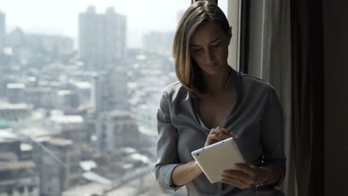 Woman Uses Tablet by the Window in City Apartment