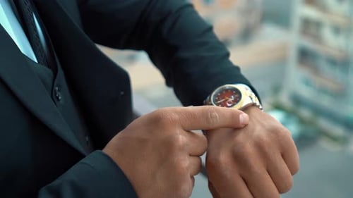 Elegant Man Adjusts Gold Watch on Balcony