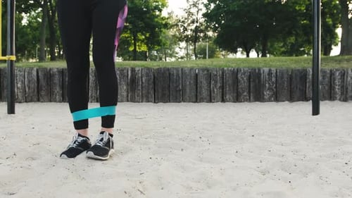Woman Exercises Legs with Resistance Band Outdoors